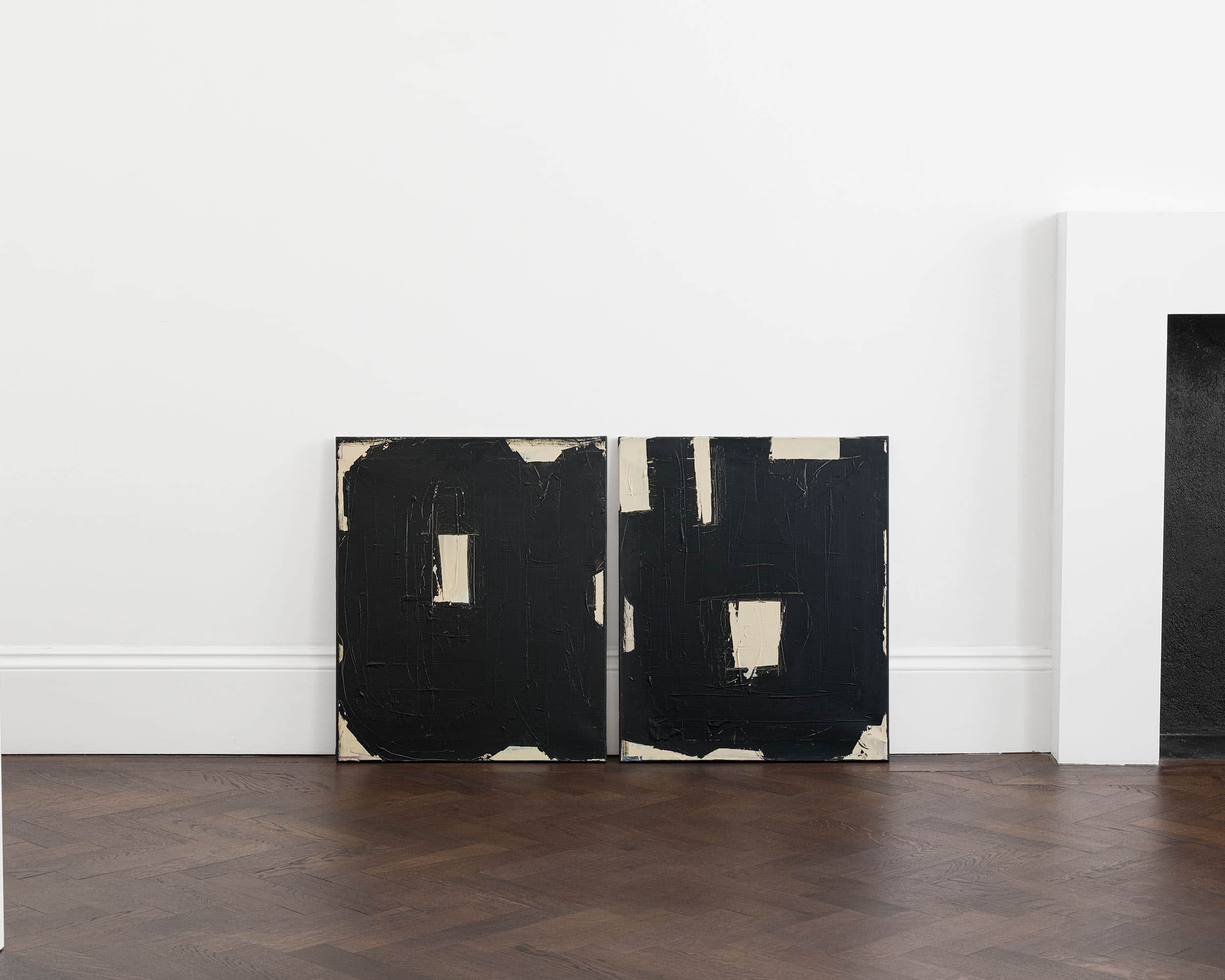 A pair of bold black and white paintings with small squares in the middle.